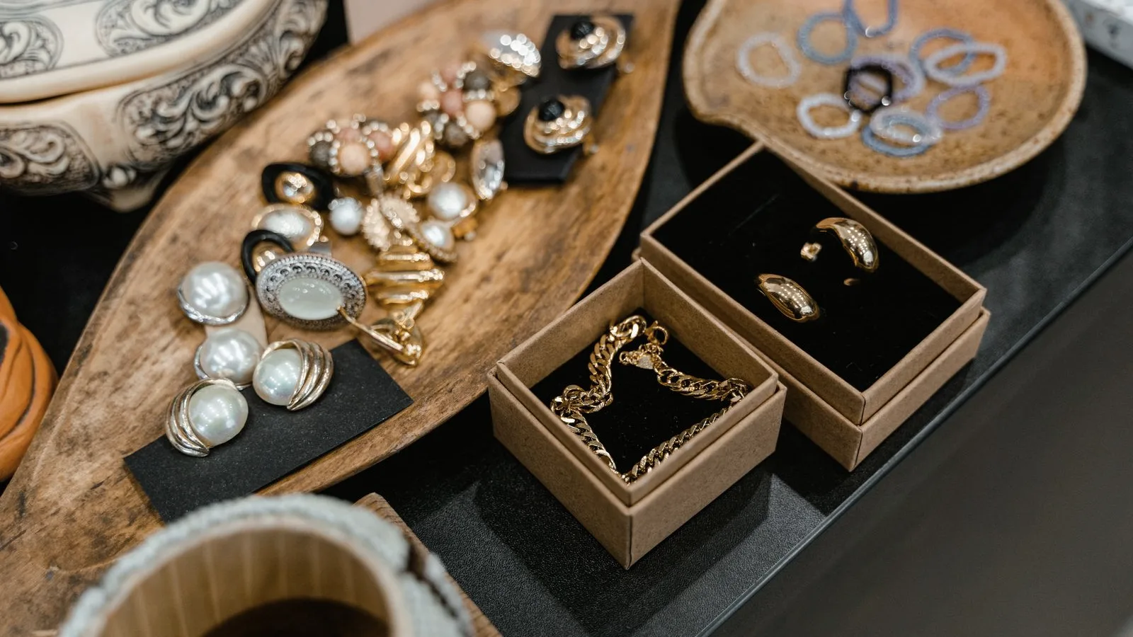 Rings, earrings, and gold jewelry arranged on a wooden tray and in small gift boxes