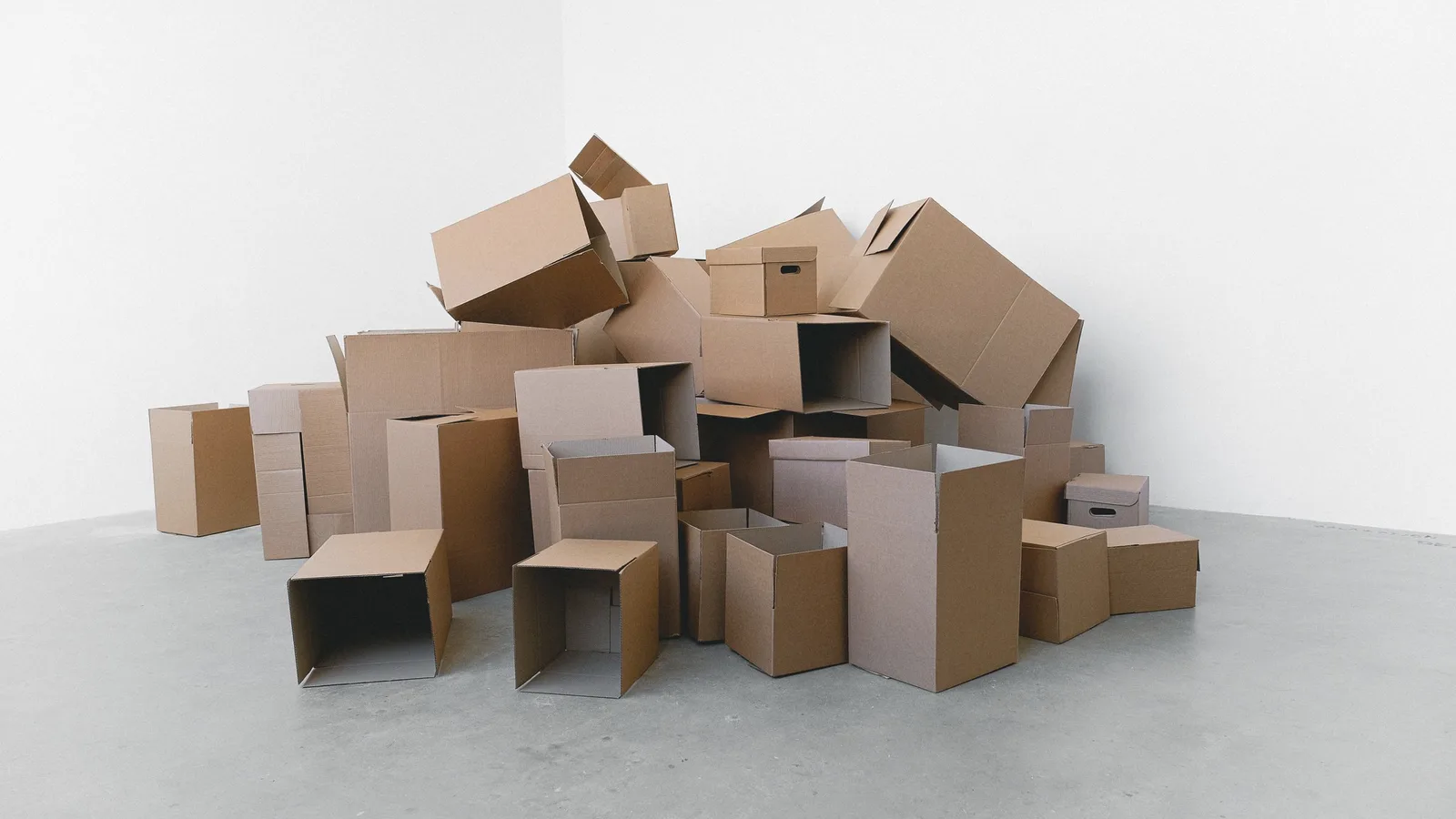 A pile of cardboard moving boxes stacked in an empty room before being loaded into storage