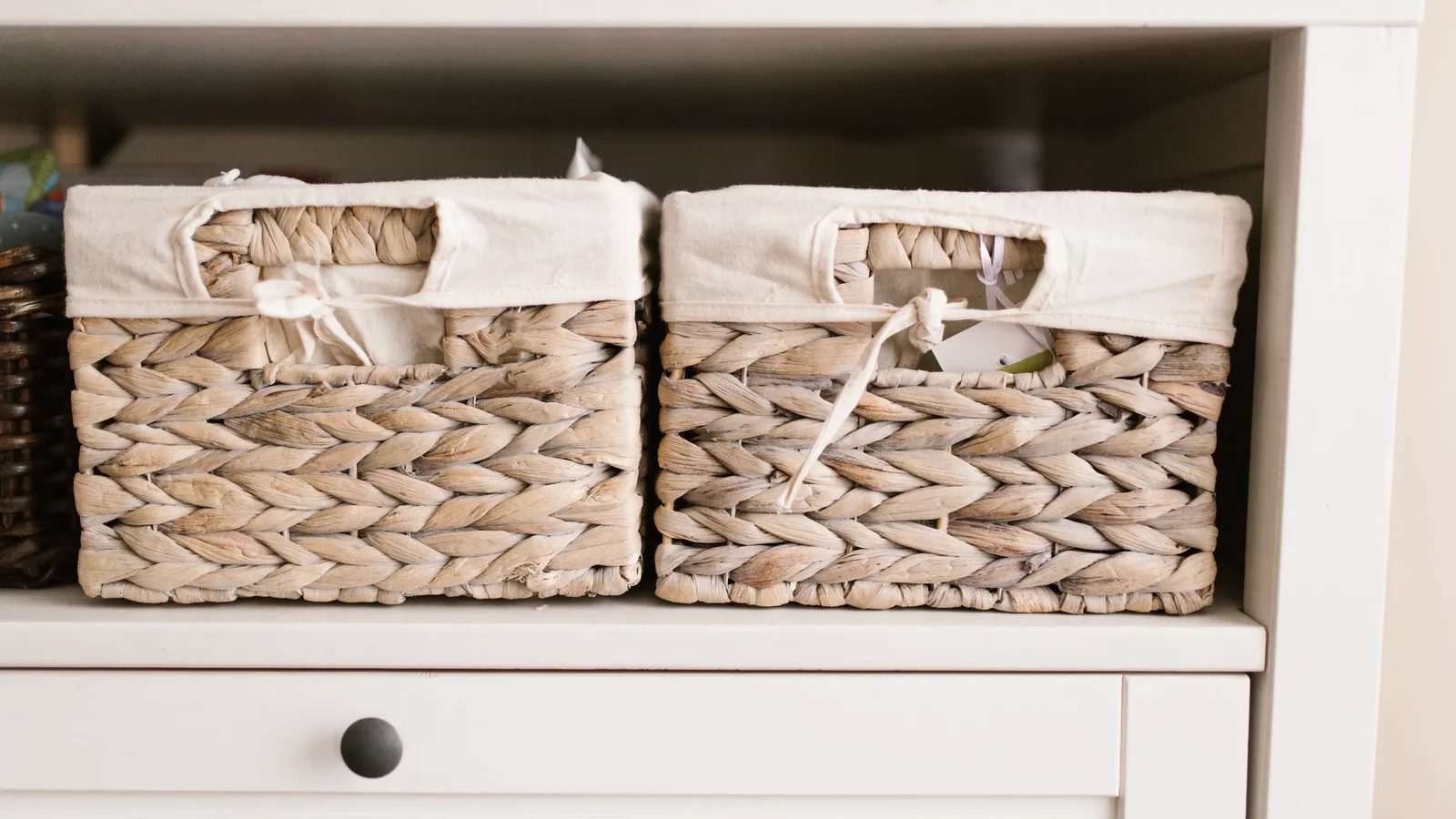 Woven storage baskets lined up on a white shelving unit